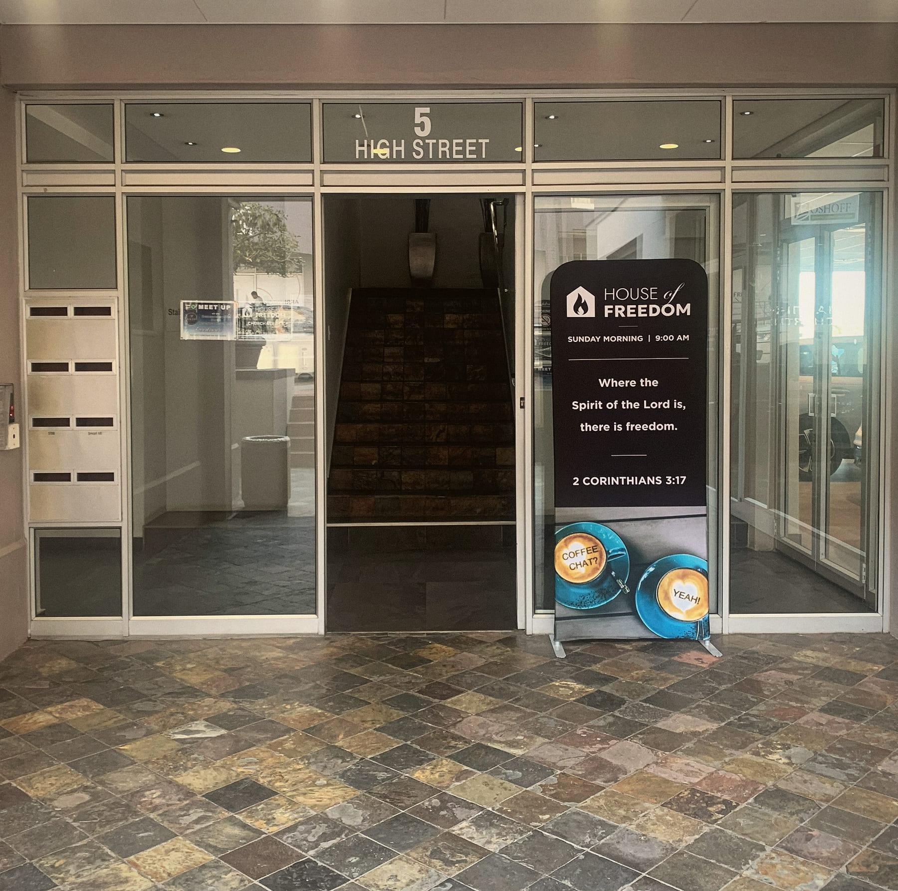 The glass entrance at 5 High Street, with a House of Freedom banner standing in the open door.